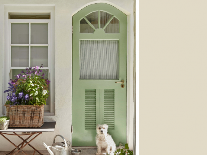 Little Greene - Green Stone Light 269 op een buitenmuur met een groene deur en een bloemenmand
