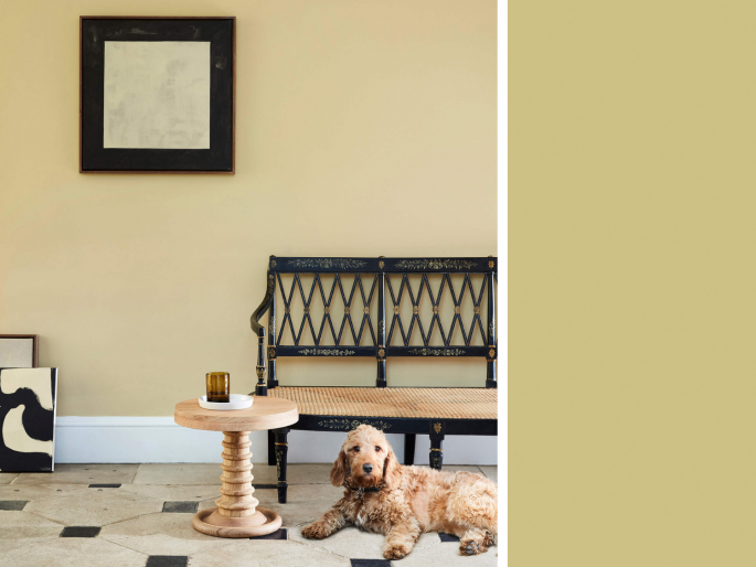 Little Greene - Oak Apple 63 op de wand toegepast met een houten bankje en tafel ervoor